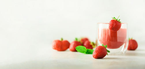 Healthy strawberry smoothie in glass on gray background with copy space. Banner. Summer food and clean eating concept, vegan diet. Pink detox beverage with fresh berries