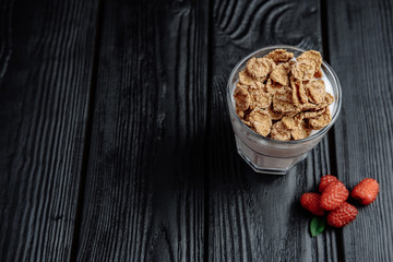 homemade yoghurt with flakes and raspberries on  dark wooden background