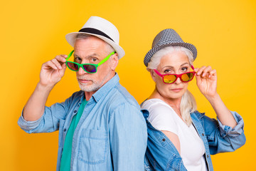 Listen to us you small little kid! We run this world! Close up photo portrait of joking funky cool stylish trendy chic he and she touching green red eyewear isolated on bright background