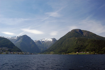 Fototapeta na wymiar Mountains and fjord in Norway. Clouds and blue sky. Beautiful stunning views of mountains, water, sky, clouds and sun. Norwegian nature. Sognefjord 