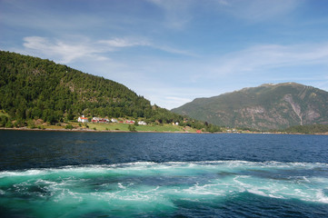 Fototapeta premium Mountains and fjord in Norway. Clouds and blue sky. Beautiful stunning views of mountains, water, sky, clouds and sun. Norwegian nature. Sognefjord 