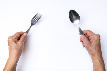 Senior woman's hands holding silver spoon and fork isolated on white background
