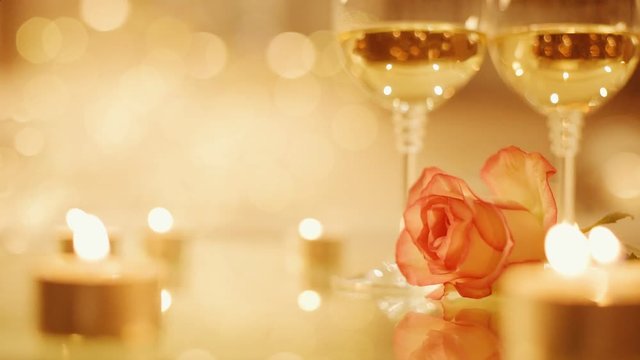 Cinemagraph - Two glasses with white wine and rose flower on bokeh background. Romantic concept. Motion Photo.