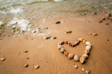 Heart shape from sea stones on a sandy ocean beach, top view, copy space. Love summer vacation background, romance concept