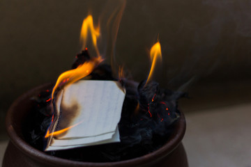 Letters on fire inside brown clay pot. Memories removal, promise commitment, burning evidence concepts