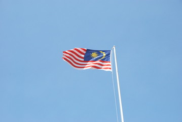 Malaysian flag waving in the wind with clear blue sky