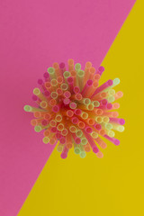 Creative view of drinking straws(neon colors) party on a two-tone background - pink and yellow.