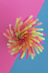 Creative view of drinking straws(neon colors) party on a two-tone background - pink and blue.