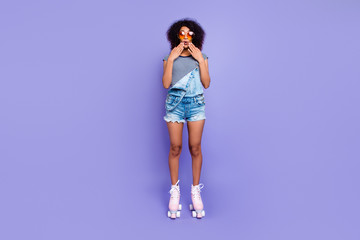 Oops! Portrait of impressed frustrated girl in eyewear riding on pink roller skates holding two...