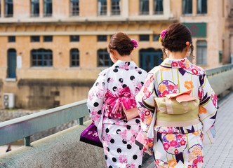 Obraz premium Two girls in a kimono on a city street, Kyoto, Japan. Back view.