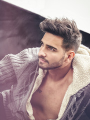 Cool young man with wool sweater on neutral background looking away to a side