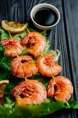 Large grilled BBQ shrimp with sweet chili sauce and lemon, salad.parsley dill celery skewer, dark background, shrimps prawns skewers with herbs