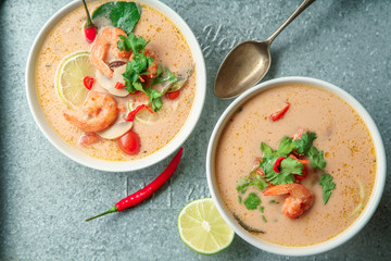Traditional thai soup tom yum with shrimps and mushrooms, served with fresh lime slices on metallic tray