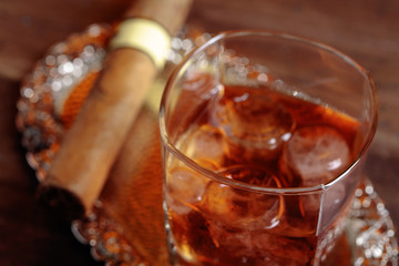 Glass of  whiskey and cigar on old wooden table.