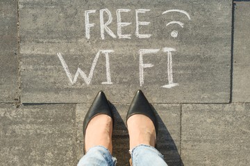 Female feet with text free wi fi written on grey sidewalk.
