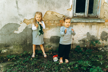 A beautiful couple of children in gray suits are playing against the background of the wall