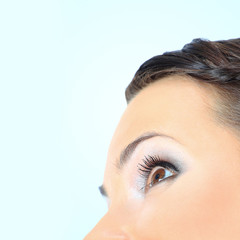 Beautiful woman's eye side view Isolated on blue background
