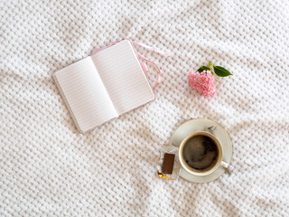 Tasse Kaffee und Notizbuch auf einer weißen Decke