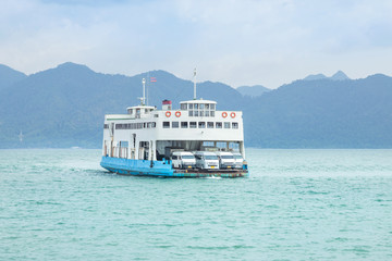 Obraz premium Large ferryboat carrying passengers and cars crossing in blue sea between Koh Chang island and Trad province, Thailand 