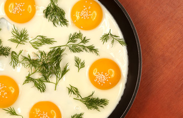 pan on the table with fried scrambled eggs with dill and sesame seeds