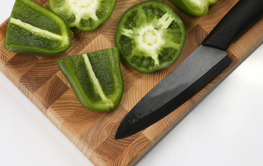 sliced sweet peppers with a ceramic knife on a wooden board