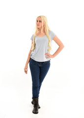 full length portrait of blonde girl wearing blue shirt and jeans, standing pose isolated on white studio background.