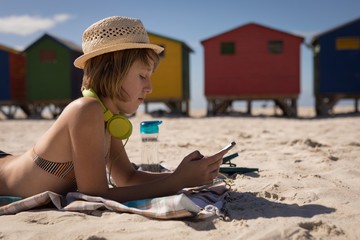 Teenage girl using mobile phone while relaxing on beach