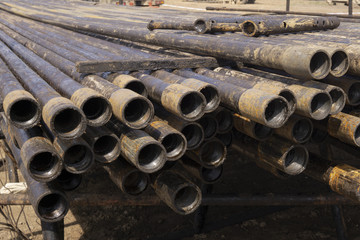 Oil Drill pipe. Rusty drill pipes were drilled in the well section. Downhole drilling rig. Laying the pipe on the deck. View of the shell of drill pipes laid in courtyard of the oil and gas warehouse.