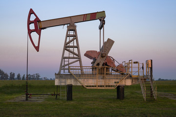 The beam pumping unit is homework, sunset in oil field. Oil pump oil rig energy industrial machine...