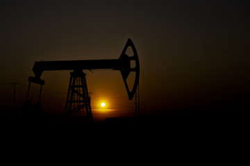 Crisis in the oil industry. The end of the era of oil deposits. Pump jack against the sun