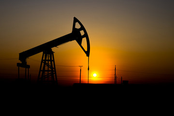 Crisis in the oil industry. The end of the era of oil deposits. Pump jack against the sun