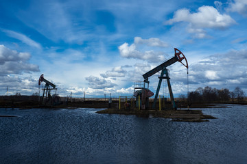 The beam pumping unit is homework, sunset in oil field. Oil pump oil rig energy industrial machine for petroleum. The pumping unit as the  pump installed on a well. Equipment of oil fields.