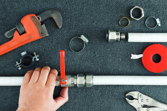 Hand repairman holding pipe and tools for repair plumbing.Concept repair home pipeline.Top view.