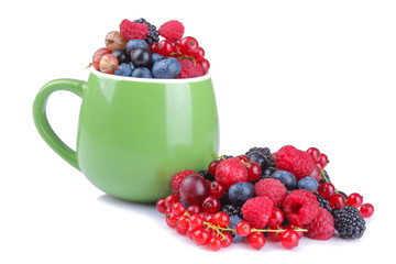 Various fresh berries close-up including blueberries, raspberries, blackberries and currants in a green cup on a white background. isolated.