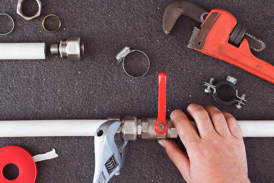 Hand repairman holding pipe and tools for repair plumbing.Concept repair home pipeline.Top view.