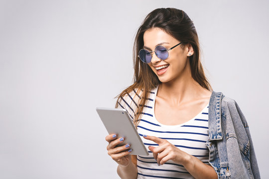 Image of cheerful young caucasian woman showing display of tablet computer. Looking aside. White background.