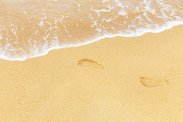 Fototapeta na wymiar footprints in wet sand with white soft wave on the tropical beach