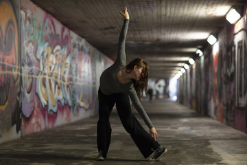 Obraz premium Female Dancer in Motion Dancing in an Urban Underpass