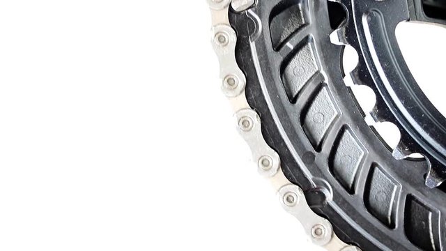 The drive gear of bicycle is rotated on a white background. Chain to drive gear wheel to bike, close-up view.