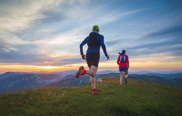 Two athletes trailrunning in the hills during sunset. Shallow D.O.F.