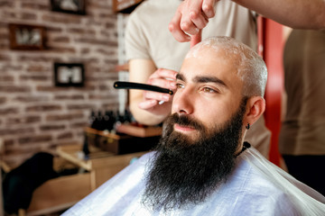 Professional master hairdresser shaves client head