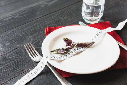 Red basil leaves on a plate together with a measuring tape. The concept of diet, lose weight.