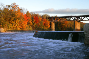 Fototapeta na wymiar Dam and bridge on the Grand River, Paris, Canada in autumn