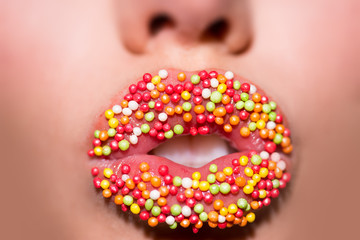 Sweet Lips. Candies. Seductive lips decorated by colorful sweet sparckles of young woman close up....
