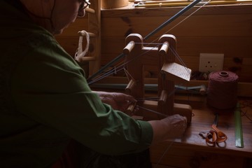Senior woman weaving silk at shop