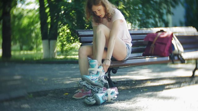 woman dresses roller skates sitting on bench in park