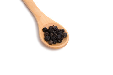 black dried pepper in wooden spoon isolated on the white
