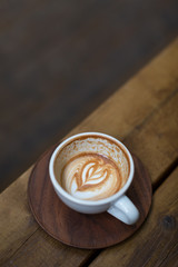 Beautiful half drinked cup of cappuccino with trendy latte art on the wooden background
