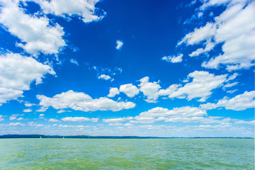 Obraz premium Summer green water lake with cloudy blue sky