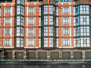 Exterior shot of new red brick residential house building with parking garage gates